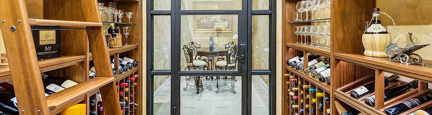 Stunning wood wine cellar custom made for a Texas home with a dramatic arched window and ladder.