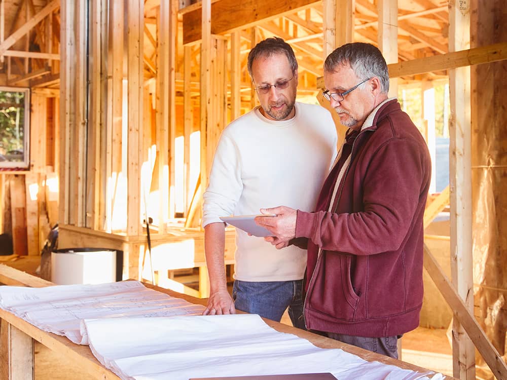 People inside an unfinished basement discussing construction.