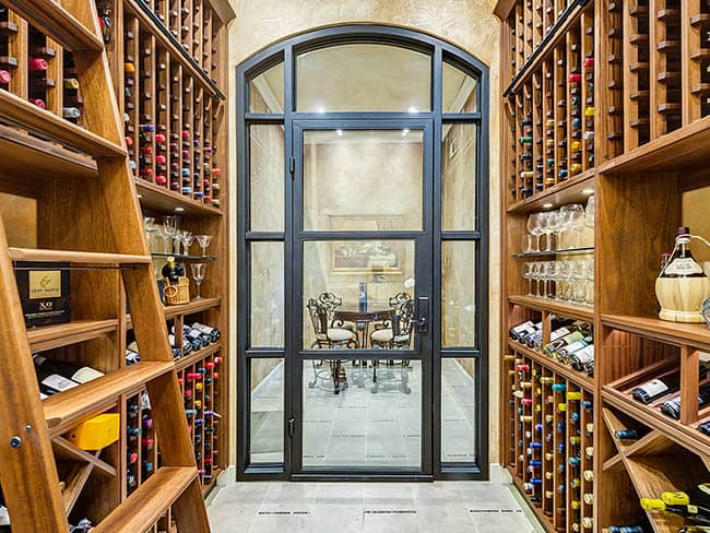 Wine cellar with arched glass door and view of dining room.