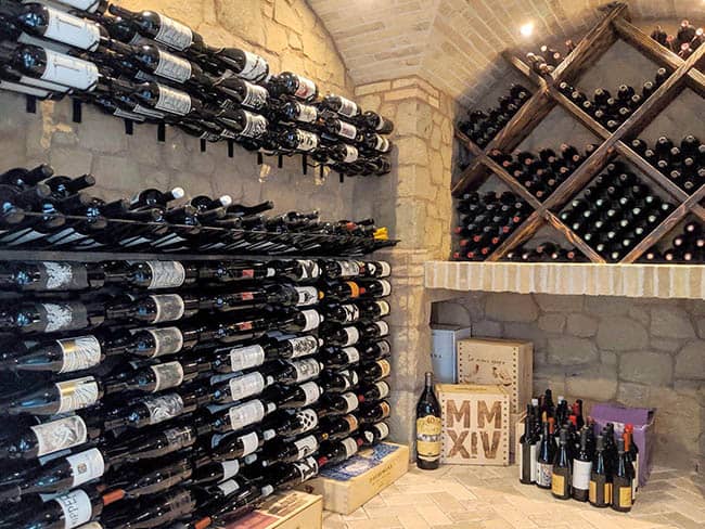 Stone wall wine cellar with floating racks of wine bottles.