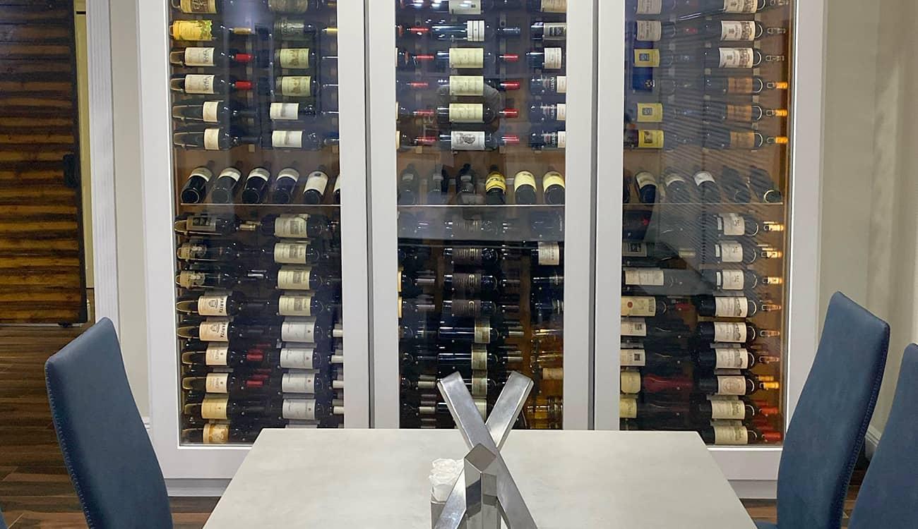 Glass enclosed wine cabinet with white edging.