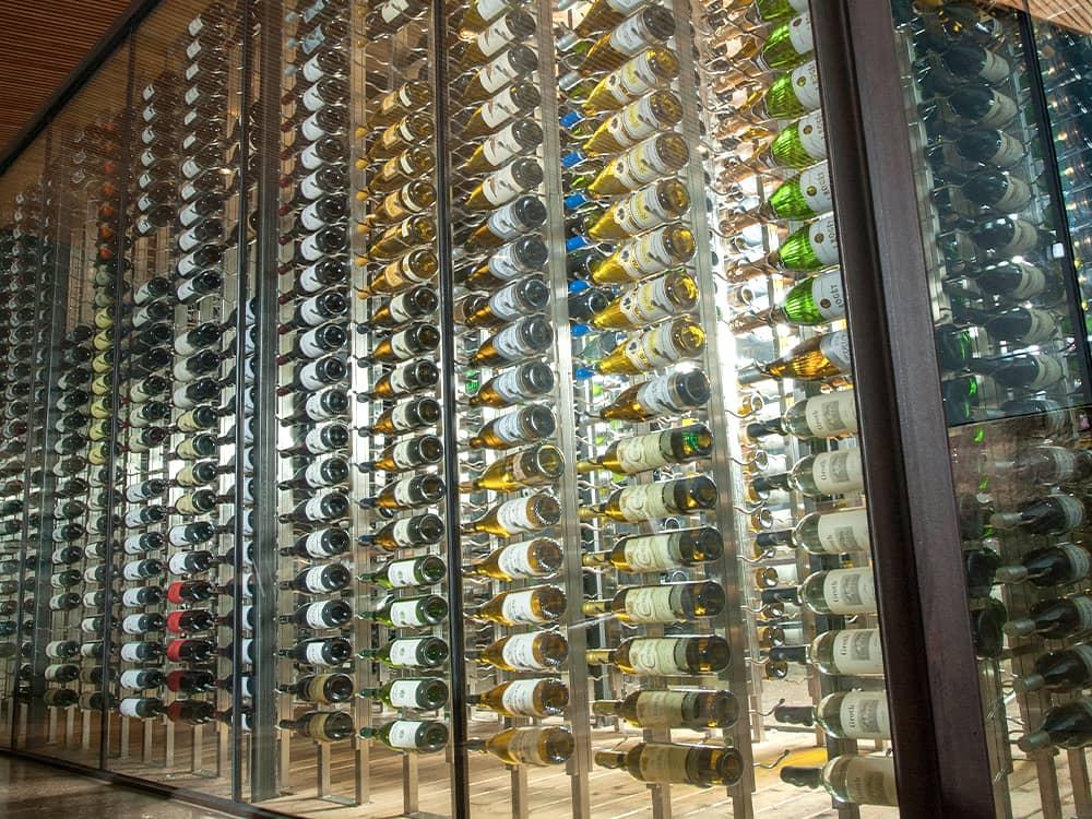 Glass enclosed wine cellar with hundreds of wine bottles.