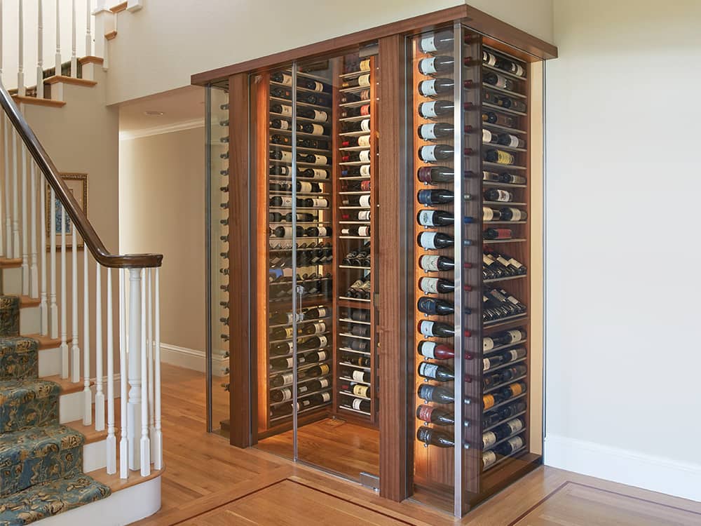 Beautiful glass enclosed wine cabinet near a staircase.