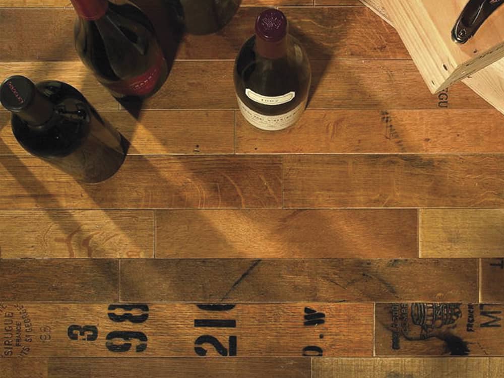 Recycled wine barrels turned into wood flooring with a wine bottle sitting on the floor